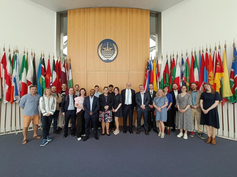 The participants of the International Tribunal for the Law of the Sea delivering its Advisory Opinion on oceans and climate change standing in front of an entrance with several flags from different countries